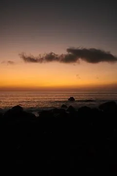 Cinematic view featuring silhouetted rocks and vibrant orange sky Stock Photos