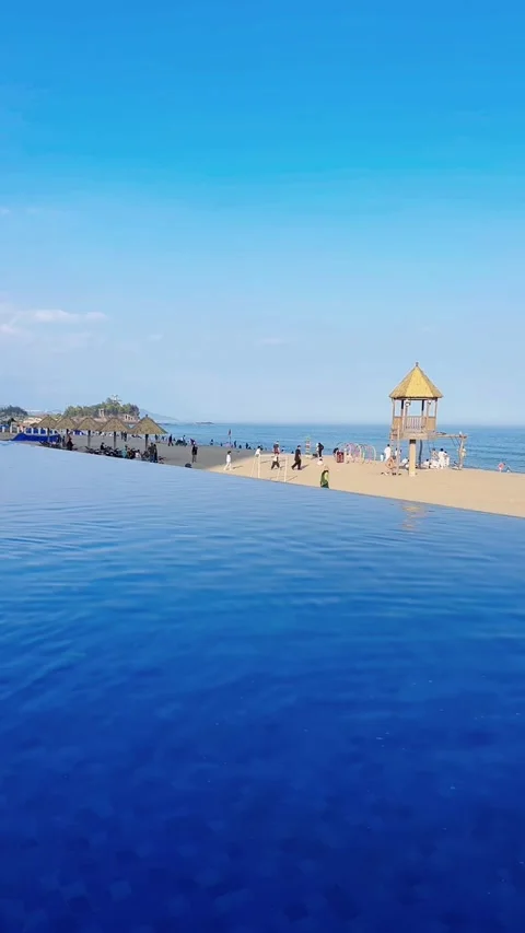 Cinematic View of Luxury Infinity Pool Overlooking Sunny Beach and Ocean Stock Footage 329079223