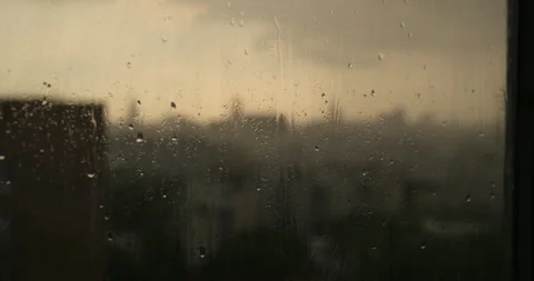 Cinematic view of rain droplets on window glass with  blurred cityscape Stock Footage 334986884