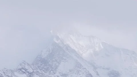 A cinematic view of a snow-covered mountain peak in the Alps, partially shrouded Stock Footage 346675959