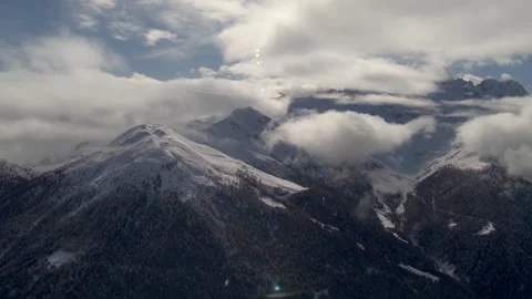 Cinematic view of snow covert mountain with clouds surrounding slide from right Vídeo Stock 330916351