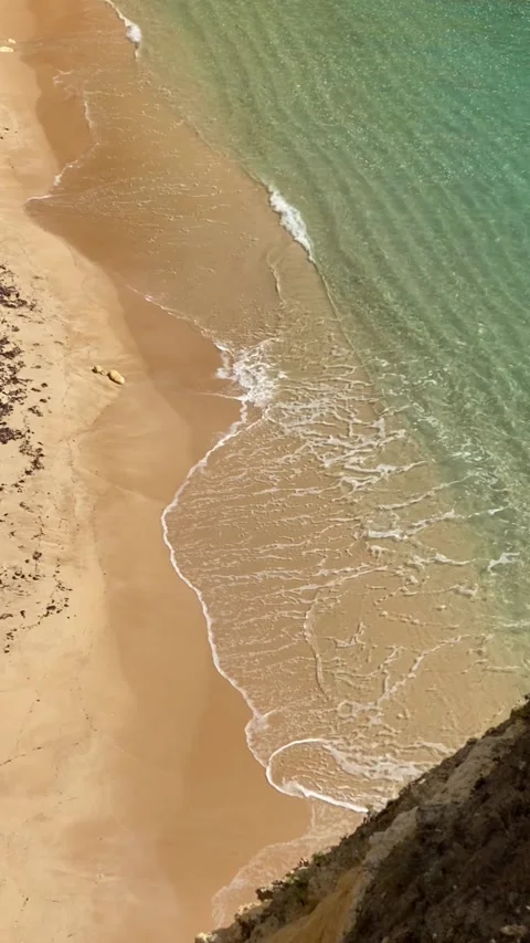 Cinematic view of turquoise waves gently reaching the sandy shore in Lagos, Port Stock Footage 315032154