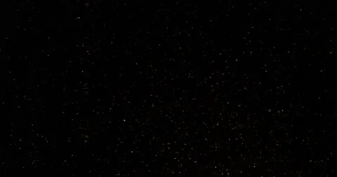 Cinematic warm dust particles floating on black background in slow motion Stock Footage 221586583