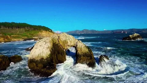 Cinematic Wide-Angle Tracking Shot of Ocean Waves Crashing Against Heart Rock 動画素材 342578584