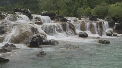 Cinematic Wide Shot of Cascading Waterfall over Rocks in Nature Stock Footage 346249087
