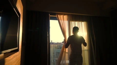Cinematic Young Man Draws Curtains Open At Sunrise Stock Footage