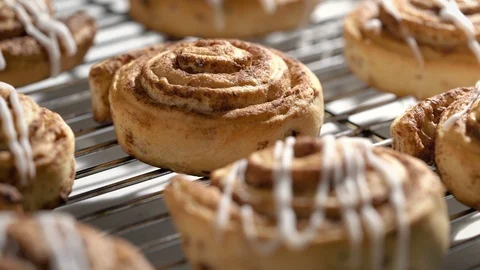 Cinnamon buns on cooling rack dripping icing. Stock Footage 96011146