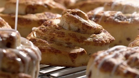 Cinnamon buns on cooling rack slow motion dripping icing. Stock Footage 96066294