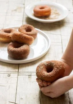Cinnamon donuts in children's hands and on a wooden table. Foto stock