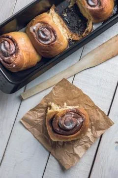 Cinnamon rolls on a black baking pan over a rustic wooden table Stock Photos