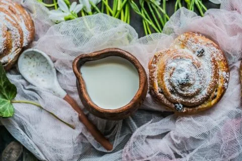 Cinnamon rolls with milk and flowers on a sunny day Stock Photos