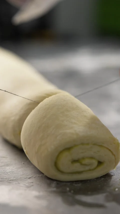 Cinnamon rolls preparation. Pastry chef cuts cinnamon roll using thread Stock Footage 320077582