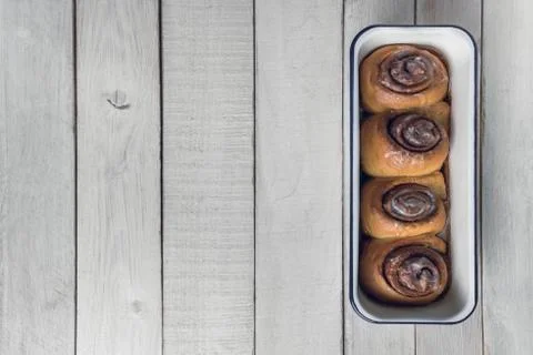 Cinnamon rolls on a white baking pan, over white rustic wooden table. Foto stock