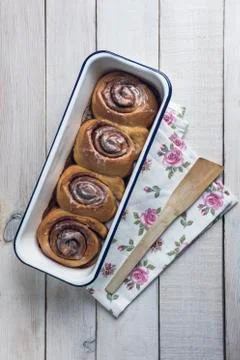 Cinnamon rolls on a white baking pan over a white rustic wooden table Stock Photos
