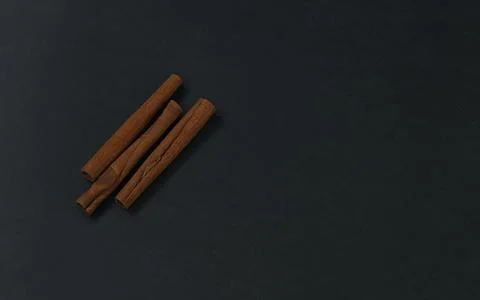 Cinnamon sticks on black background, flatlay in dark key Stock Photos