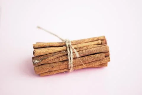 Cinnamon sticks held together with jute rope on the pink background Stock Photos