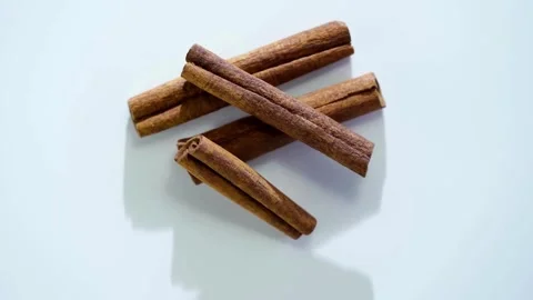 Cinnamon sticks rotating on a clean white background surface Stock Footage 333809306