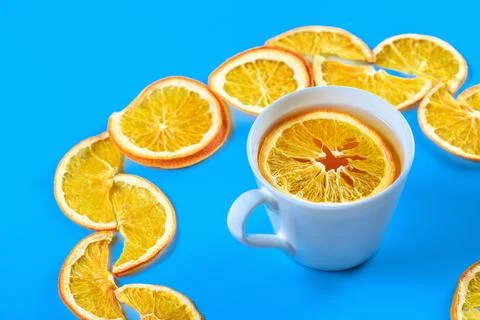 Circle of dried oranges with mug of tea on blue background Stock Photos