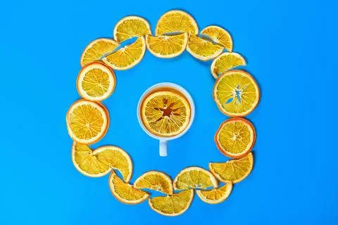 Circle of dried oranges with mug of tea on blue background Stock Photos