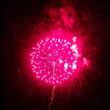 Circle explosion of festive real fireworks with red smoke on black background Stock Photos