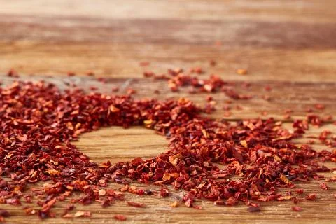 Circle framing made of dried chilly flakes on rustic wooden background, top view 写真素材