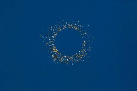 Circle gold glitter splash with empty center on blue background. Stock Photos