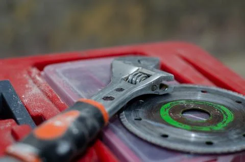 The circle for the grinder and the adjustable wrench are on the red tool box. Stock Photos