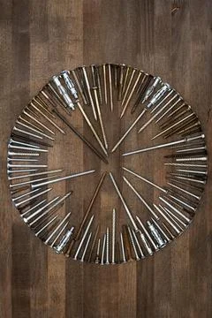 Circle made of various screws and nails on brown wood texture Stock Photos