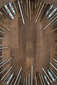 Circle made of various screws and nails on brown wood texture Stock Photos