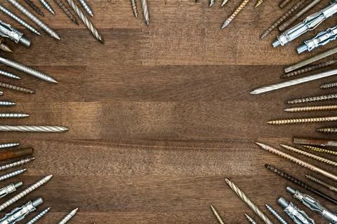 Circle made of various screws and nails on brown wood texture Stock Photos