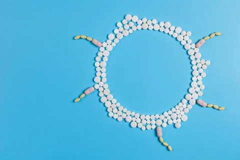 The circle is made up of white tablets on a blue background Stock Photos