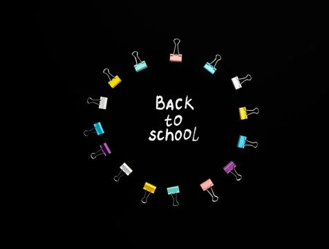 Circle of multi-colored paper clips with white handmade inscription back to Stock Photos