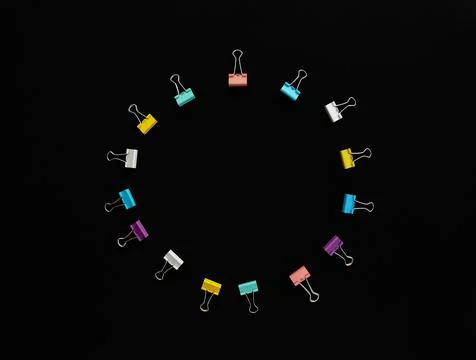Circle of multi-colored paper clips with copy space in middle on black Stock Photos