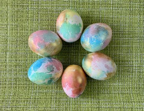 A circle of pastel-colored Easter eggs rests on a bright green textured surface, Stock Photos