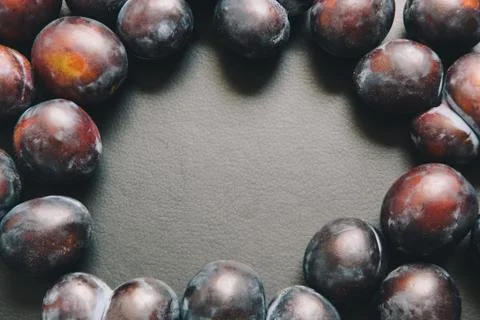 Circle of plums fruit on black background with copy space Stock Photos