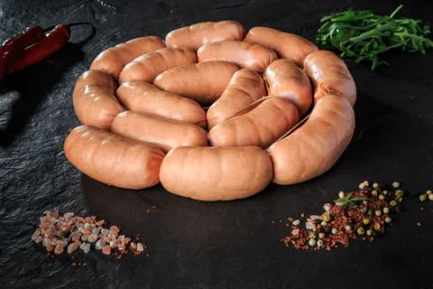Circle set of raw short thick sausages with salt, rucola and chili 스톡 사진