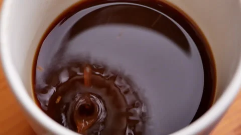 Circle shaped coffee water drops falling into coffee in a white cup. close up Stock Footage 157086232