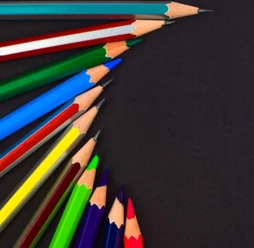 Circle shaped row made with different colored pencil crayons arranged on a bl Stock Photos