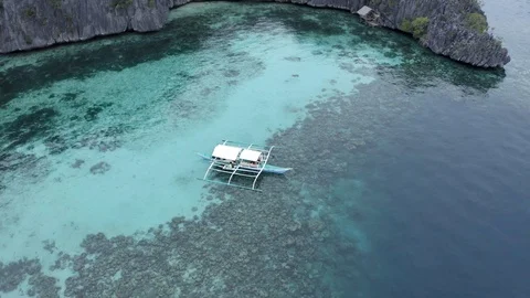 Circle tracking drone shot of a boat with colorful seabed Stock Footage 102395800