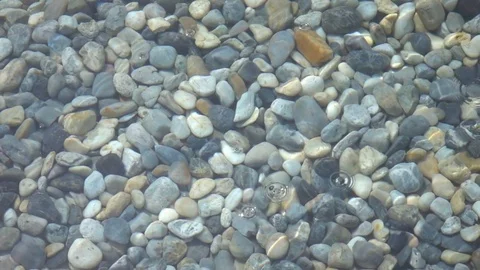 Circles flow on clear water from drops against stone background. Slow motion. 스톡 동영상 69792817