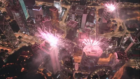 Circling aerial drone shot of exploding fireworks on top of high-rise Stock Footage 230386168
