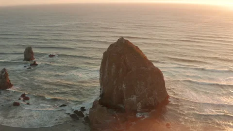 Circling aerial shot of Haystack rock sea stack at sunset Stock Footage 250064355