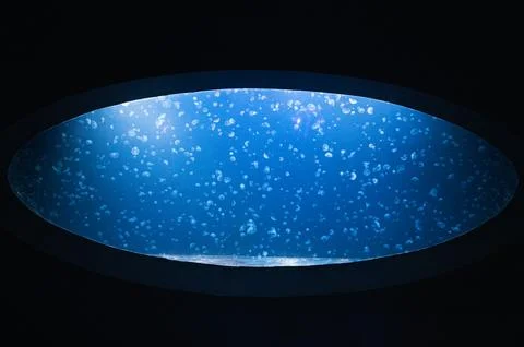 Circular blue oculus over speckled cosmos, framed by dark concrete ceiling, s Stock Photos