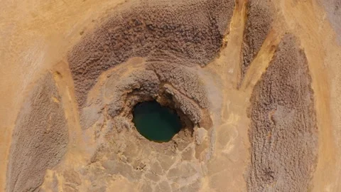 Circular collapse pit with emerald water and radiating tracks — aerial nadir Stock Footage 315157919