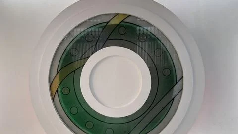Circular decorative glass panel with interwoven green and yellow patterns 库存照片