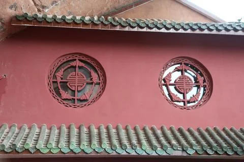 Circular decorative windows on a red wall with green tile roof Stock Photos