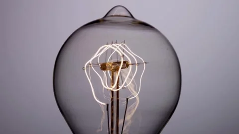 Circular filaments in edison bulb glow then dim slowly Stock Footage 329657324