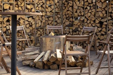 A circular fire pit surrounded by rustic wooden chairs on a backyard patio,.. 스톡 사진