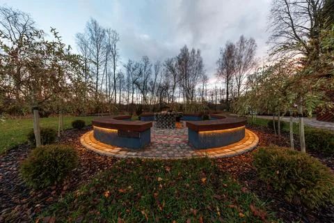 Circular fire ring lounge at dusk with underlit wooden benches Stock Photos