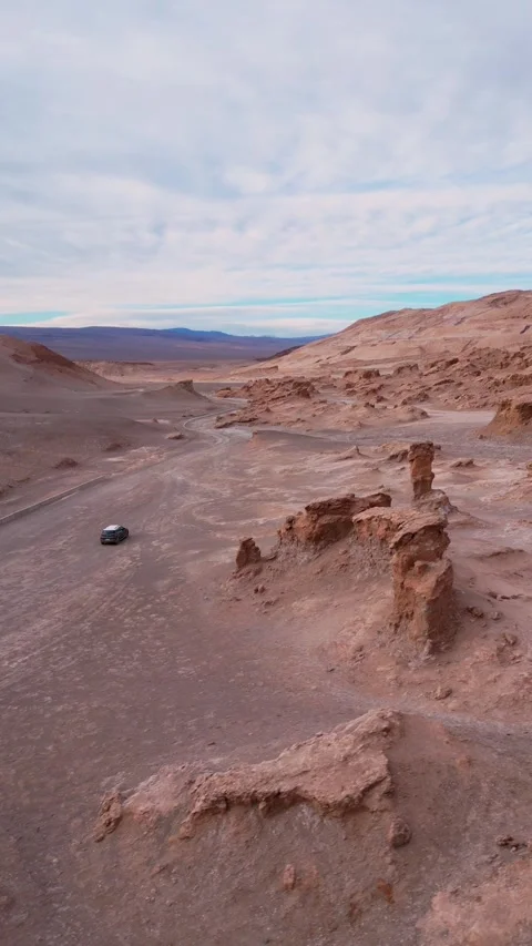 Circular flight around dark car on desert road passing dramatic rock spires and Stock Footage 340814834